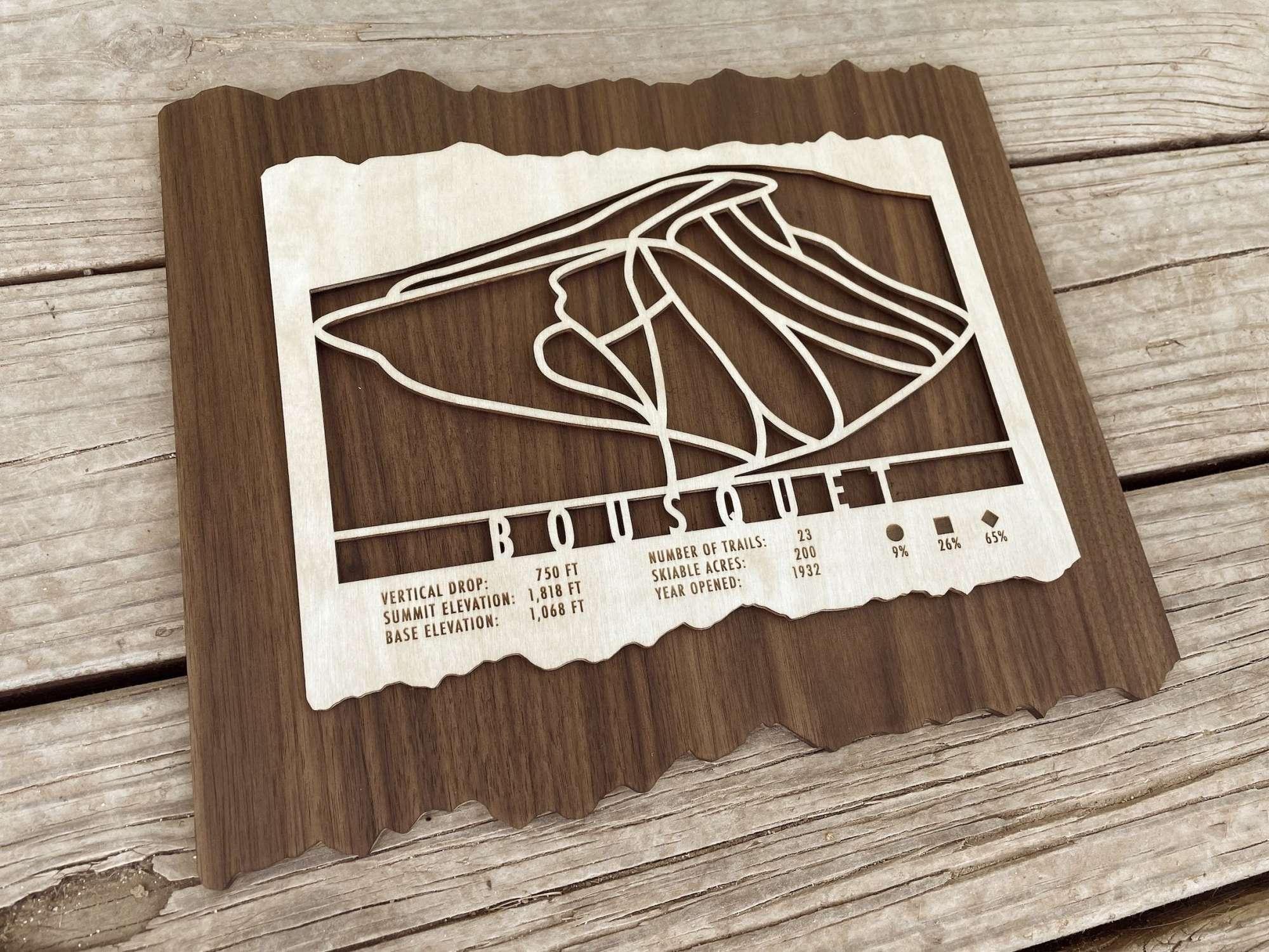Angled view of Bousquet Ski Trail Map in wood, showcasing detailed ski trail cutouts and engraved resort stats for ski-themed home decor.