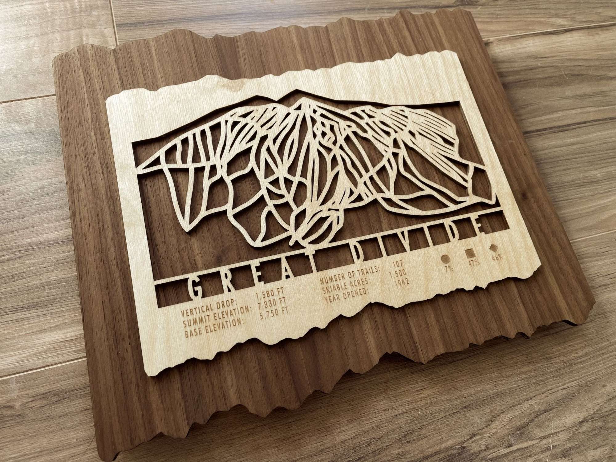 Wooden Great Divide Ski Trail Map by Mountaincut shown on hardwood floor, ideal rustic ski decor for home or mountain lodge walls.
