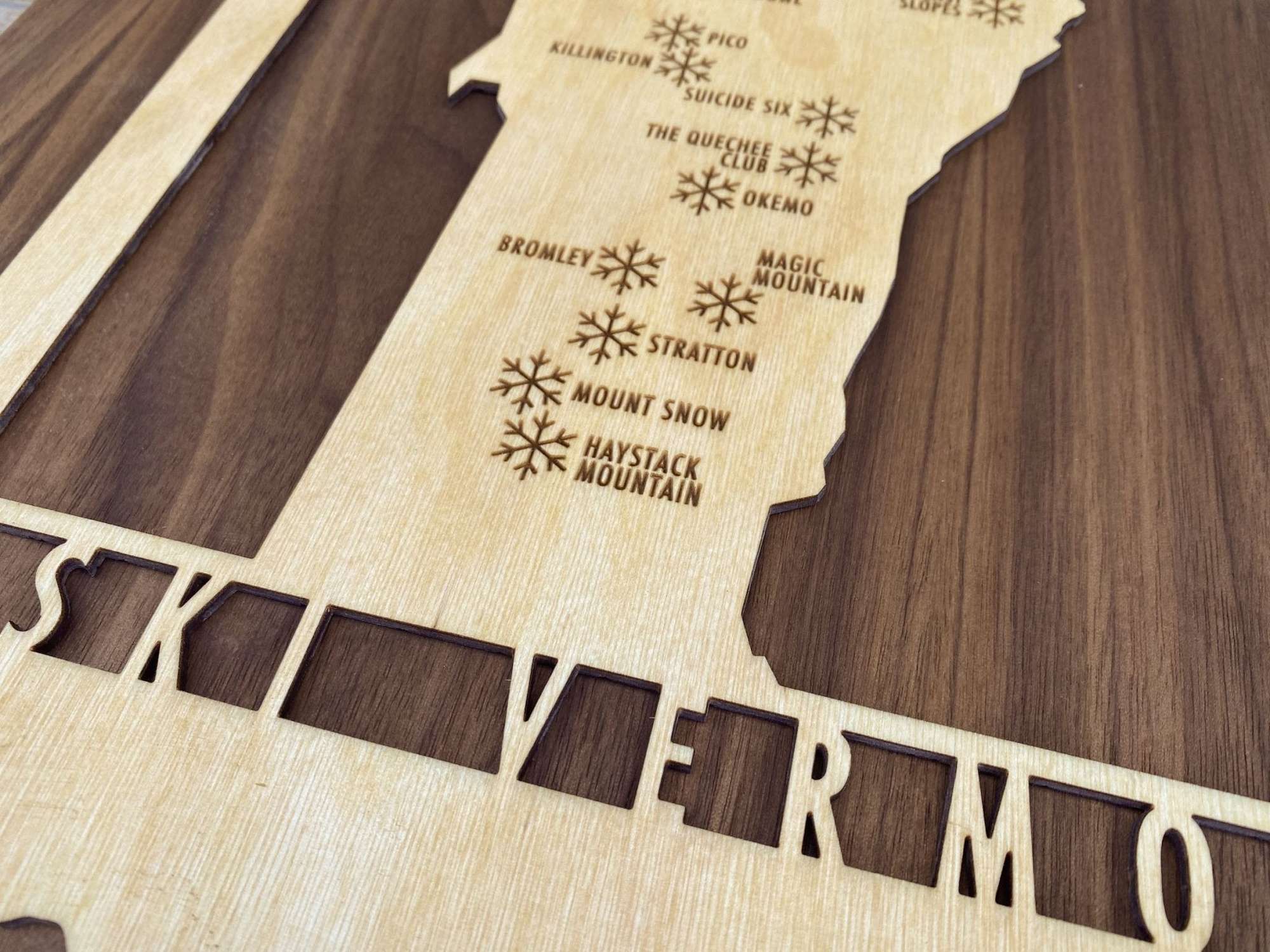 Engraved southern Vermont ski resorts on wood map decor, highlighting Stratton, Mount Snow, and Okemo.