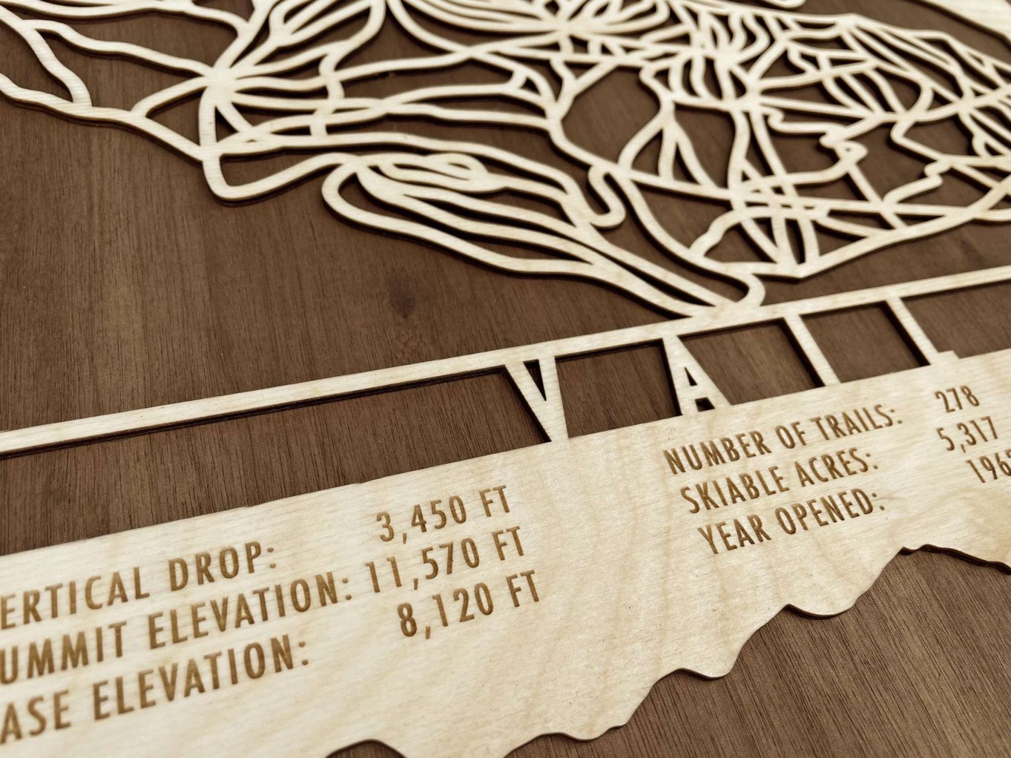 Detailed shot of Vail Ski Trail Map wood wall art showing trail layout and engraved text for vertical drop and summit elevation.