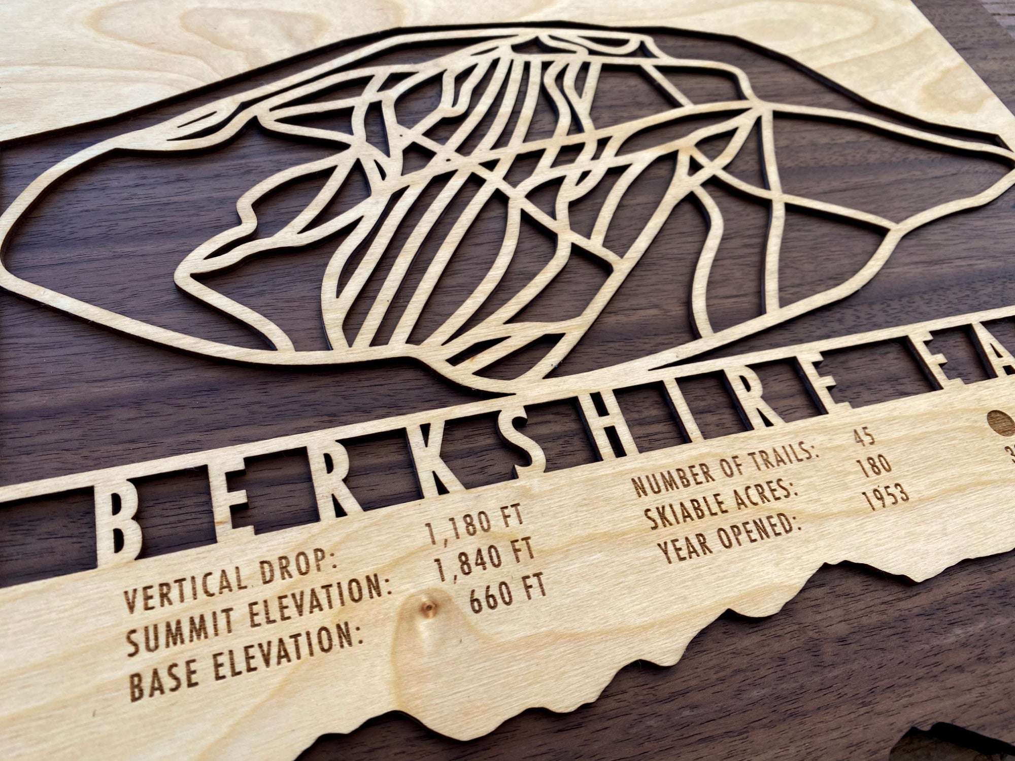 Close-up of Berkshire East wood ski map showing trail layout, vertical drop, summit elevation, and number of trails engraved in detail.