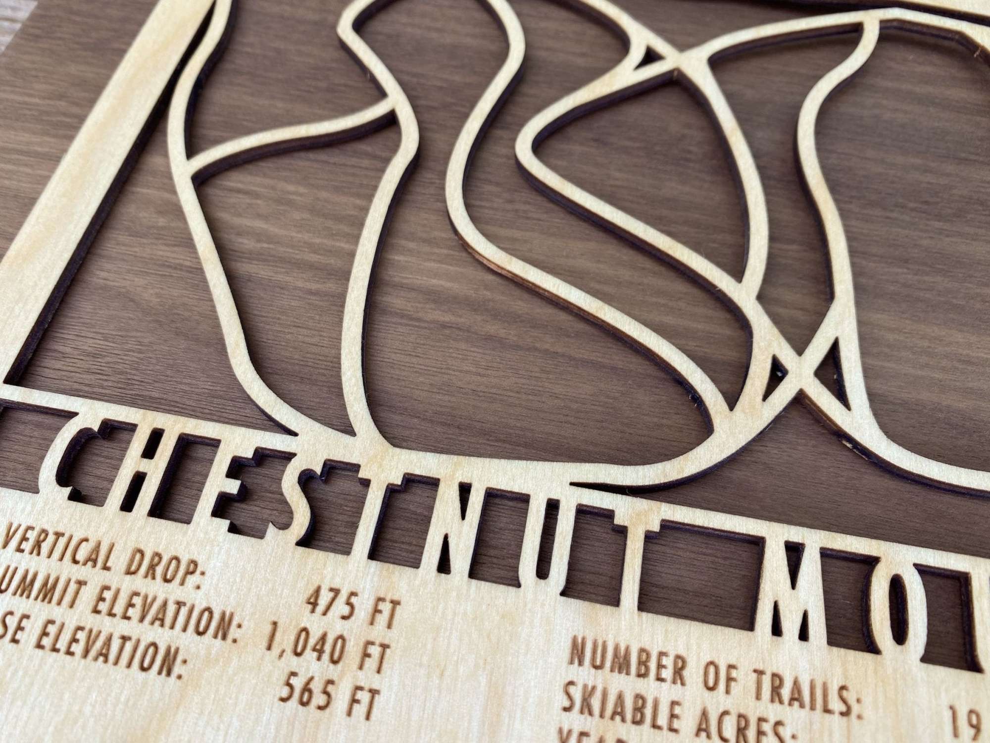 Detailed close-up of Chestnut Mountain wood ski map highlighting laser-cut trail lines and engraved text on natural wood.