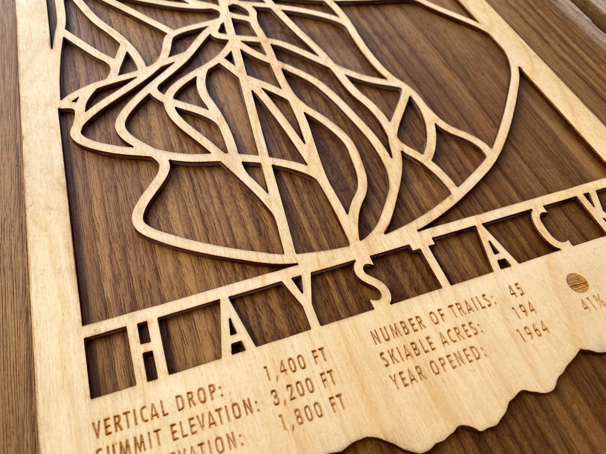 Close-up of Haystack Mountain Trail Map - Wall Decor - MountainCut showing engraved ski trail details and resort statistics on wood.