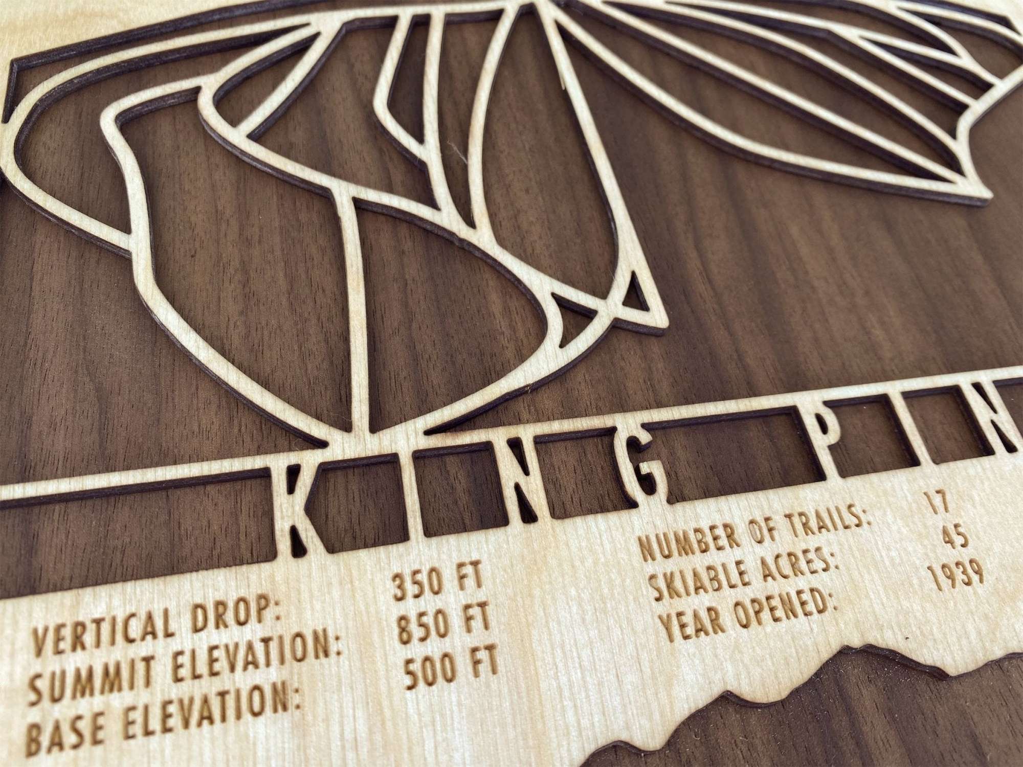 King Pine Ski Trail Map - Wall Decor - close-up of engraved trail lines and resort statistics on wood, showcasing fine craftsmanship and detail.