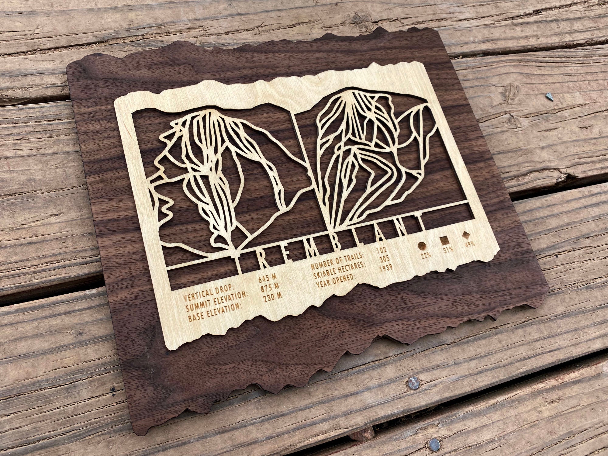 Angled view of Mont Tremblant wood ski trail map showing engraved trail layout and elevation details on dark wood backing.