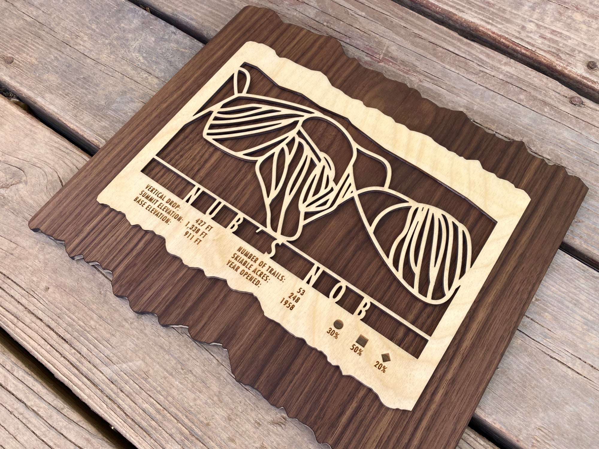 Close-up angled shot of Nub's Nob Ski Trail Map in wood, highlighting intricate trail design and engraved resort data for ski lovers.