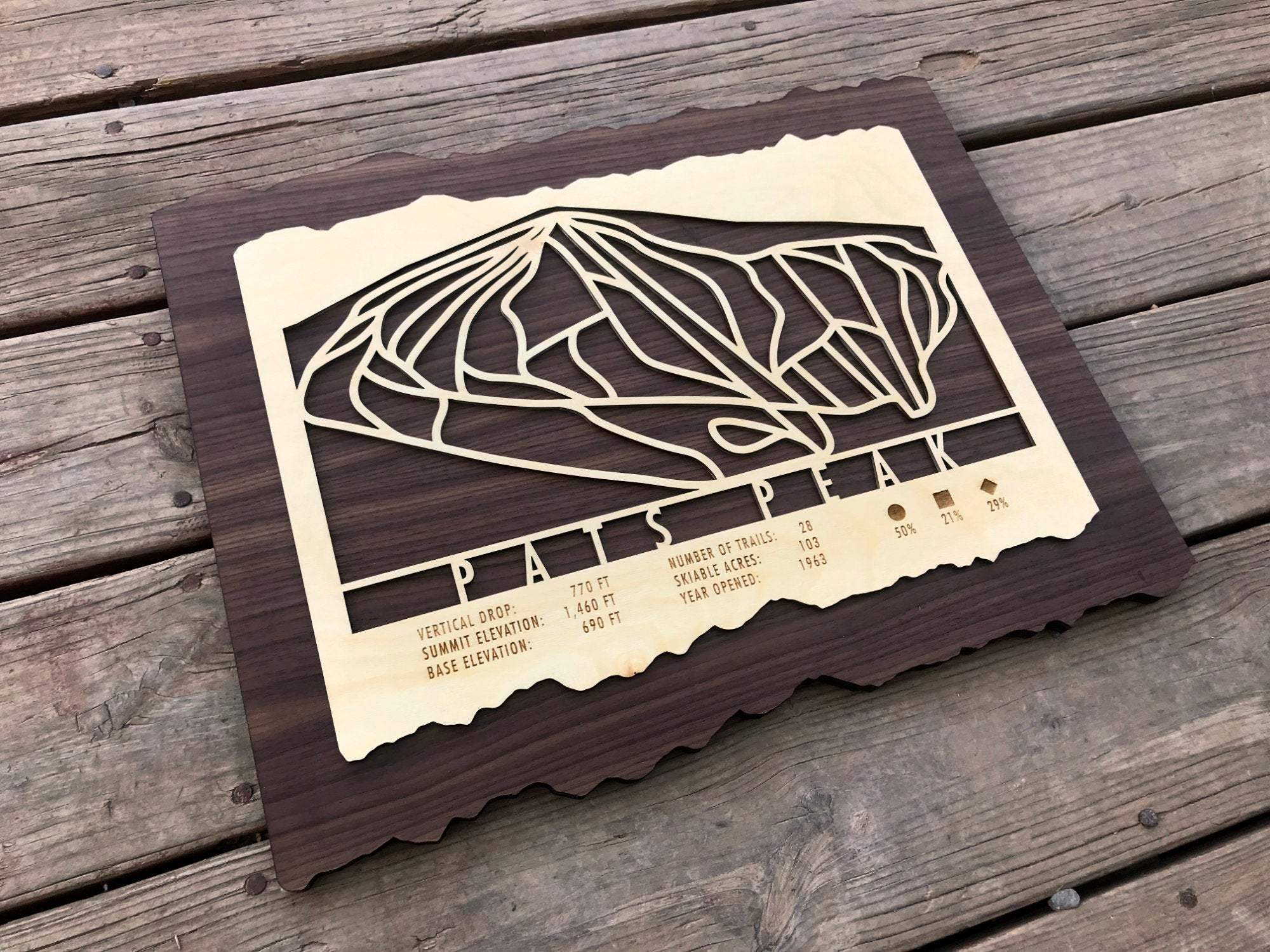 Angled view of Pats Peak Ski Trail Map - Wood Ski Decor on wood background, showcasing intricate trail layout and engraved elevation details.