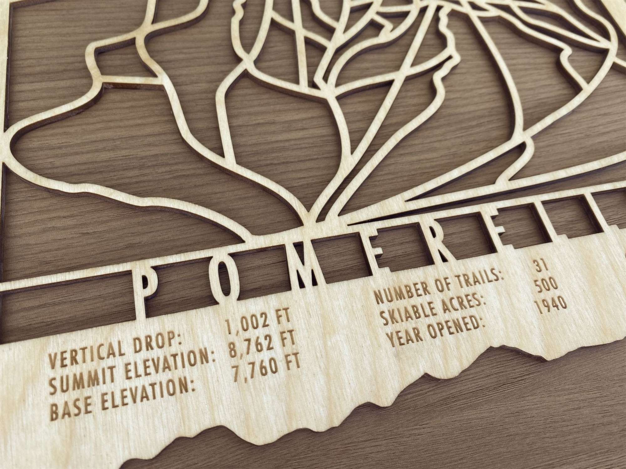 Detailed view of Pomerelle Ski Trail Map with engraved elevation, trail count, and skiable acres, crafted in wood for ski lodge wall art.