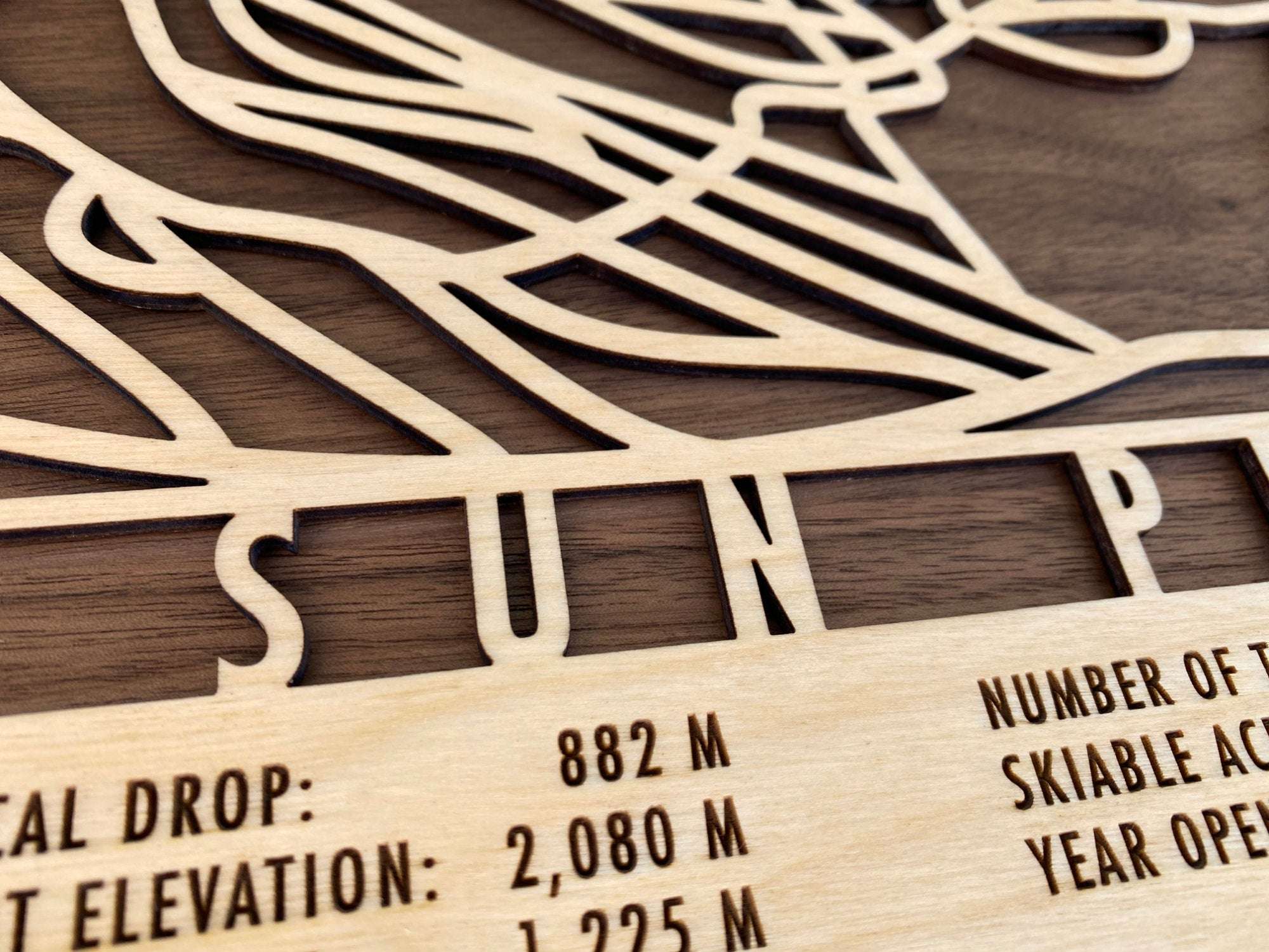 Close-up of Sun Peaks wood ski map highlighting precision laser-cut lettering and trail details, premium decor for ski enthusiasts.