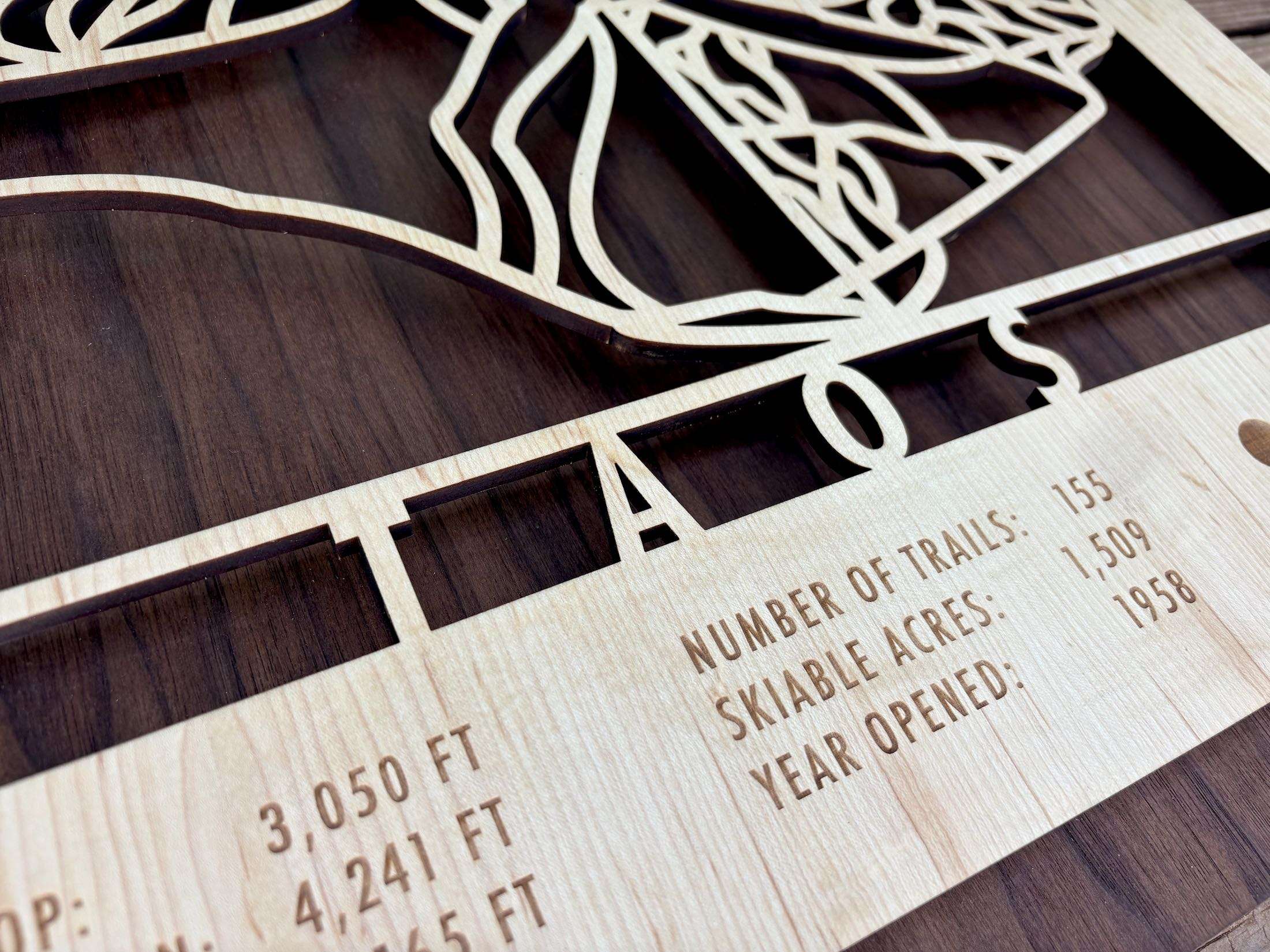 Close-up of Taos Ski Trail Map - Personalized Wood Ski Decor - Mountaincut highlighting engraved trail count, acreage, and year opened.