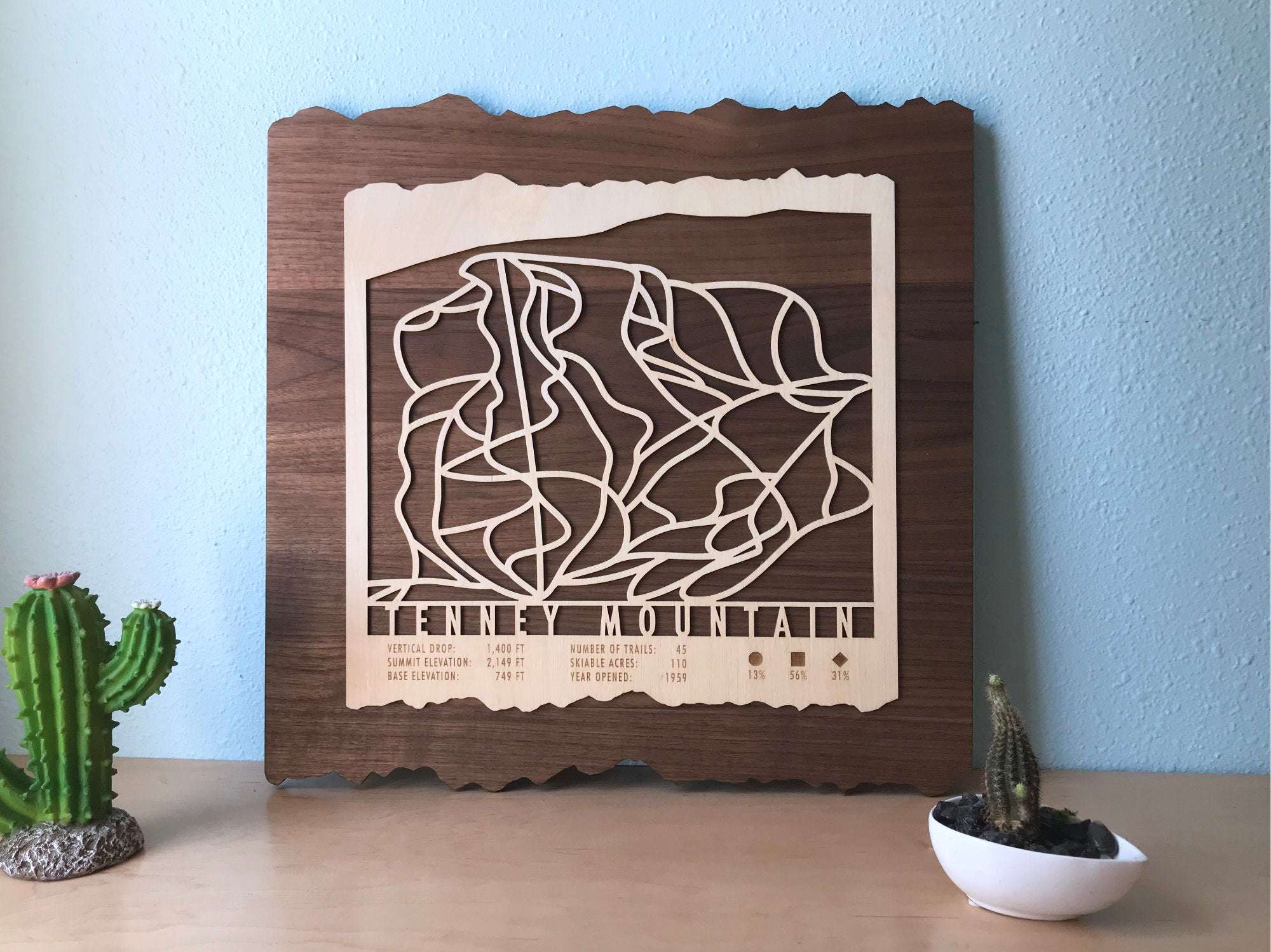 Tenney Mountain Ski Trail Map - Wood Ski Decor displayed on a wall with cacti, showcasing its rustic charm for home or office decor.