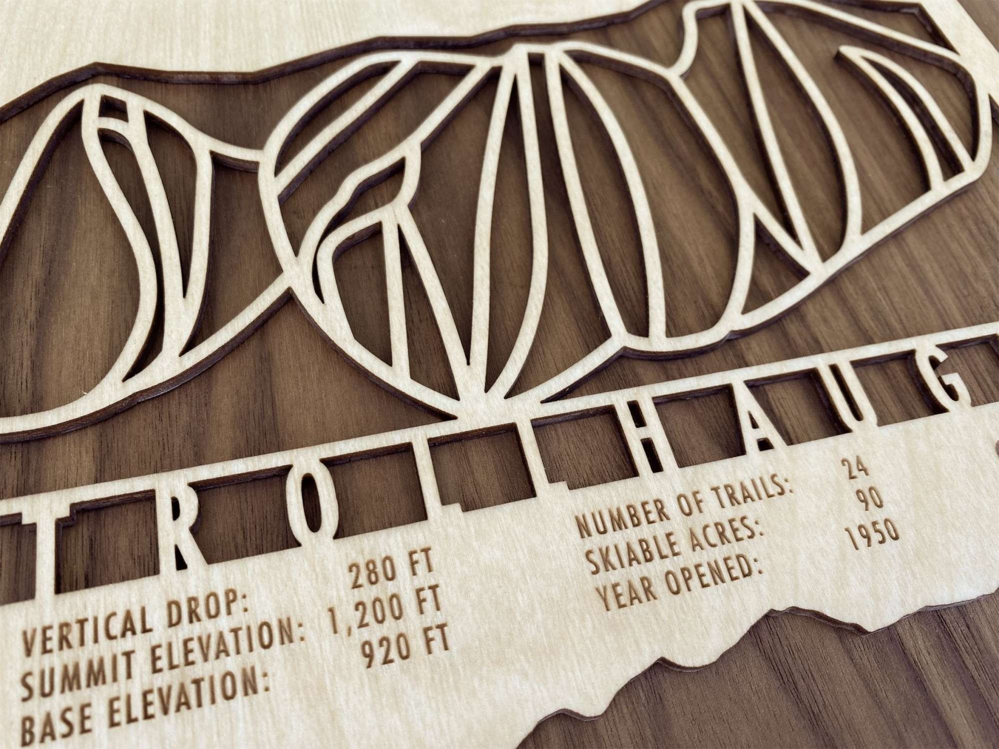 Close-up of Trollhaugen wood ski map showing engraved trail stats and intricate mountain cutout, a unique skier gift idea.