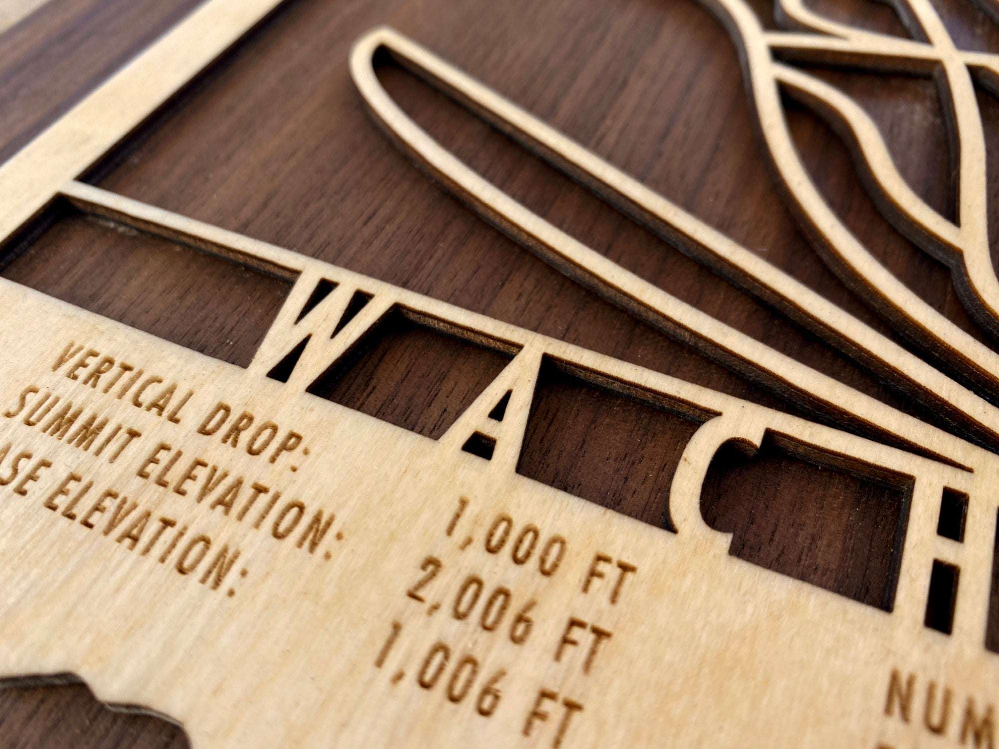 Detailed close-up of engraved text on Wachusett Ski Trail Map wood decor, highlighting vertical drop, summit elevation, and base elevation.