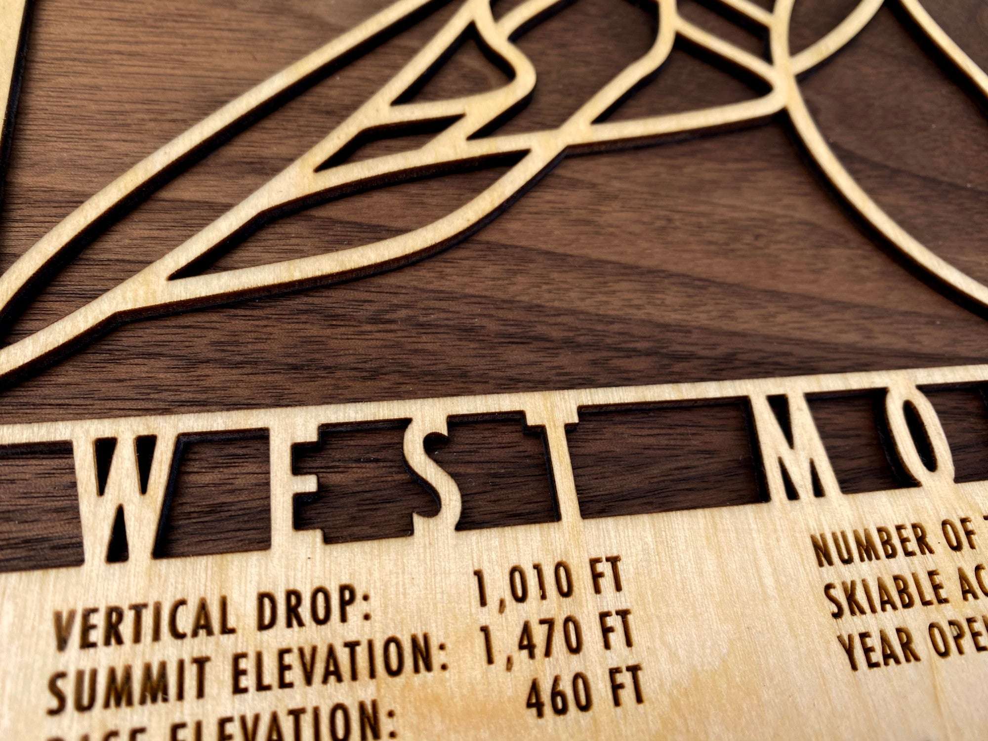 Close-up of West Mountain wood ski map showing detailed laser engraving of trail names and elevations, crafted for ski enthusiasts' wall decor.