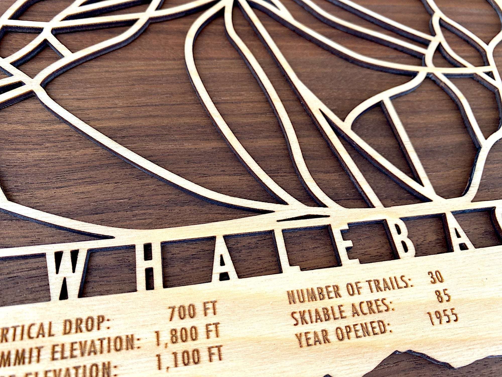 Close-up of Whaleback Mountain wood ski trail map with engraved trail names and mountain stats, a unique gift for skiers and snowboarders.
