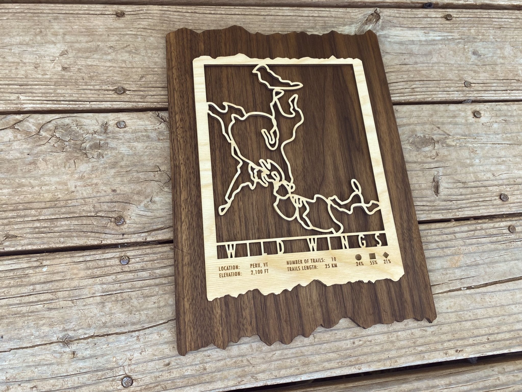 Angled view of Wild Wings Trail Map - showcasing engraved wooden cross country ski trail design on natural wood background.