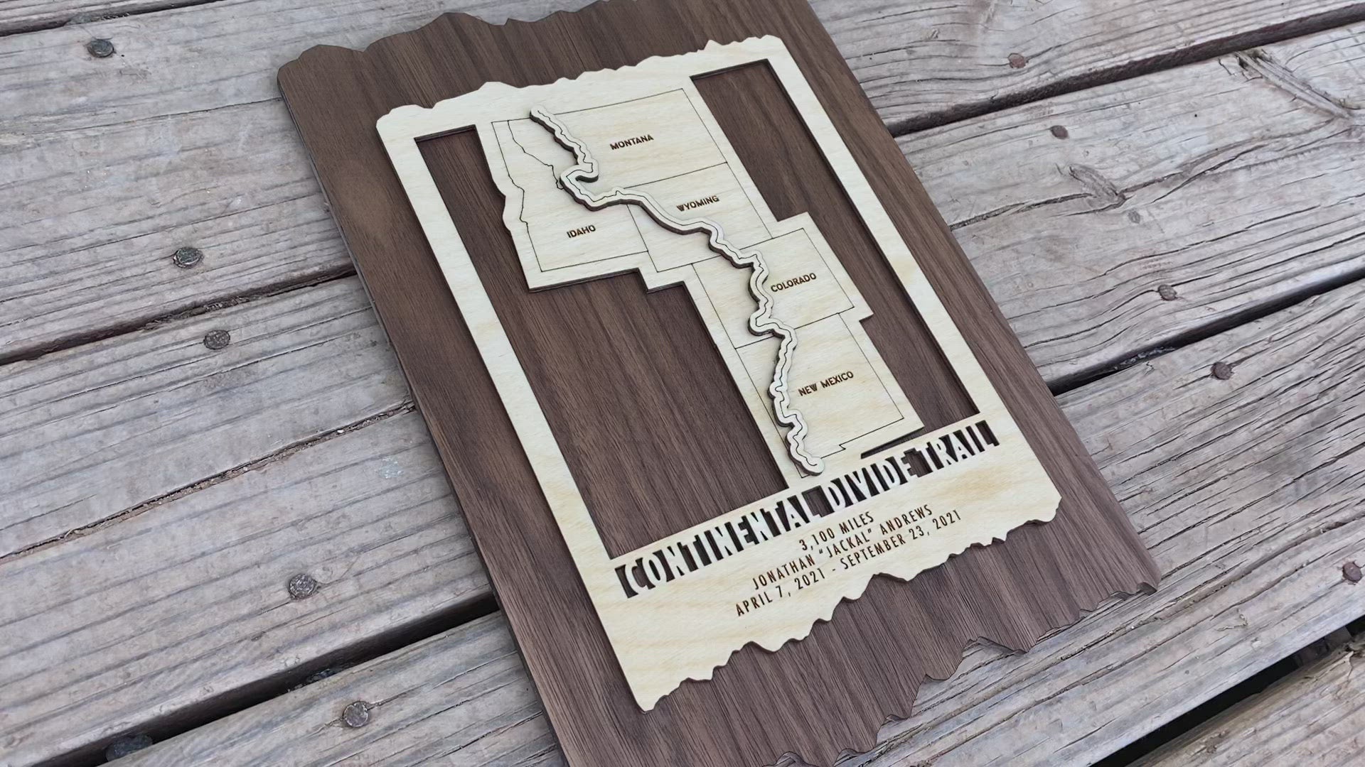 Angled view of Continental Divide Trail wood wall map showing engraved trail route and personalized hiking details on dark wood.